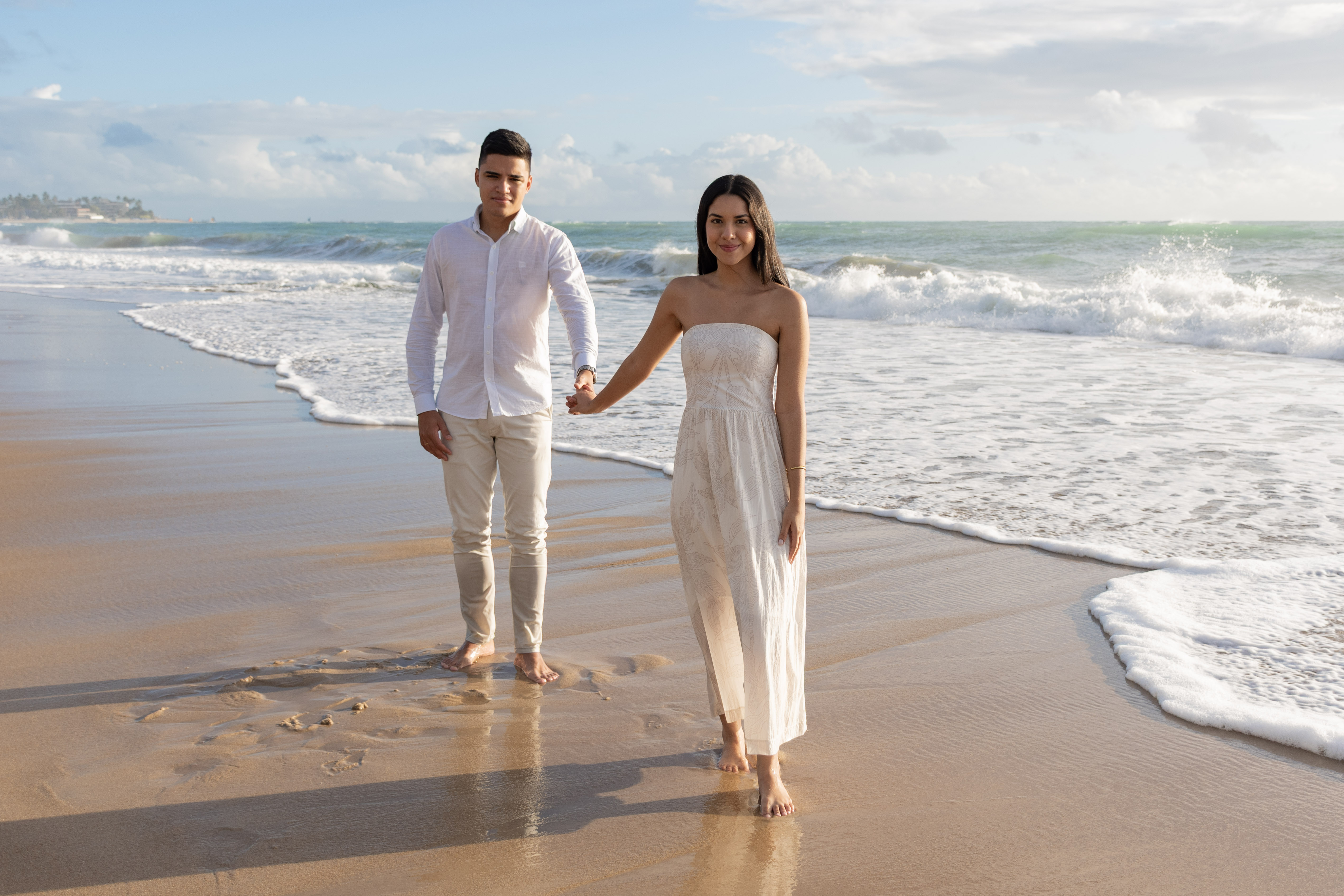 Casal sorridento com pé na areia durante ensaio fotográfico em Porto de Galinhas